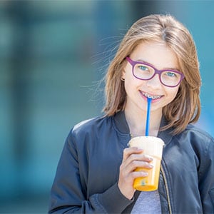 preteen girl with braces smiling holding drink